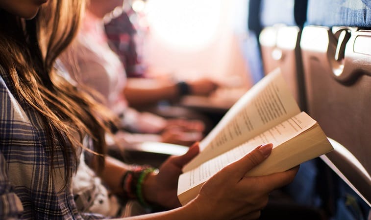 Menina lendo livro em avião