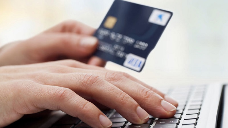 Pessoa com cartão de crédito e computador