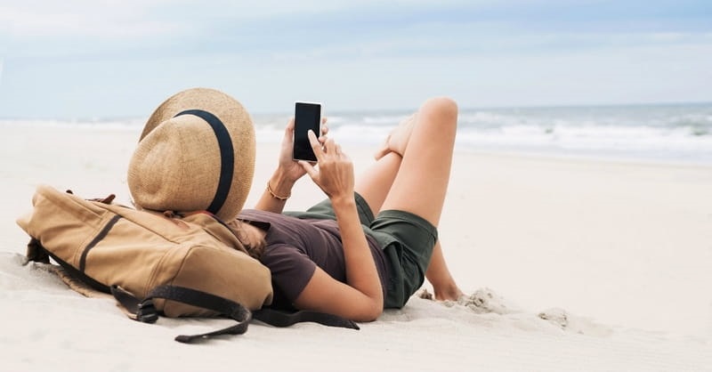 Menina usando o celular em praia